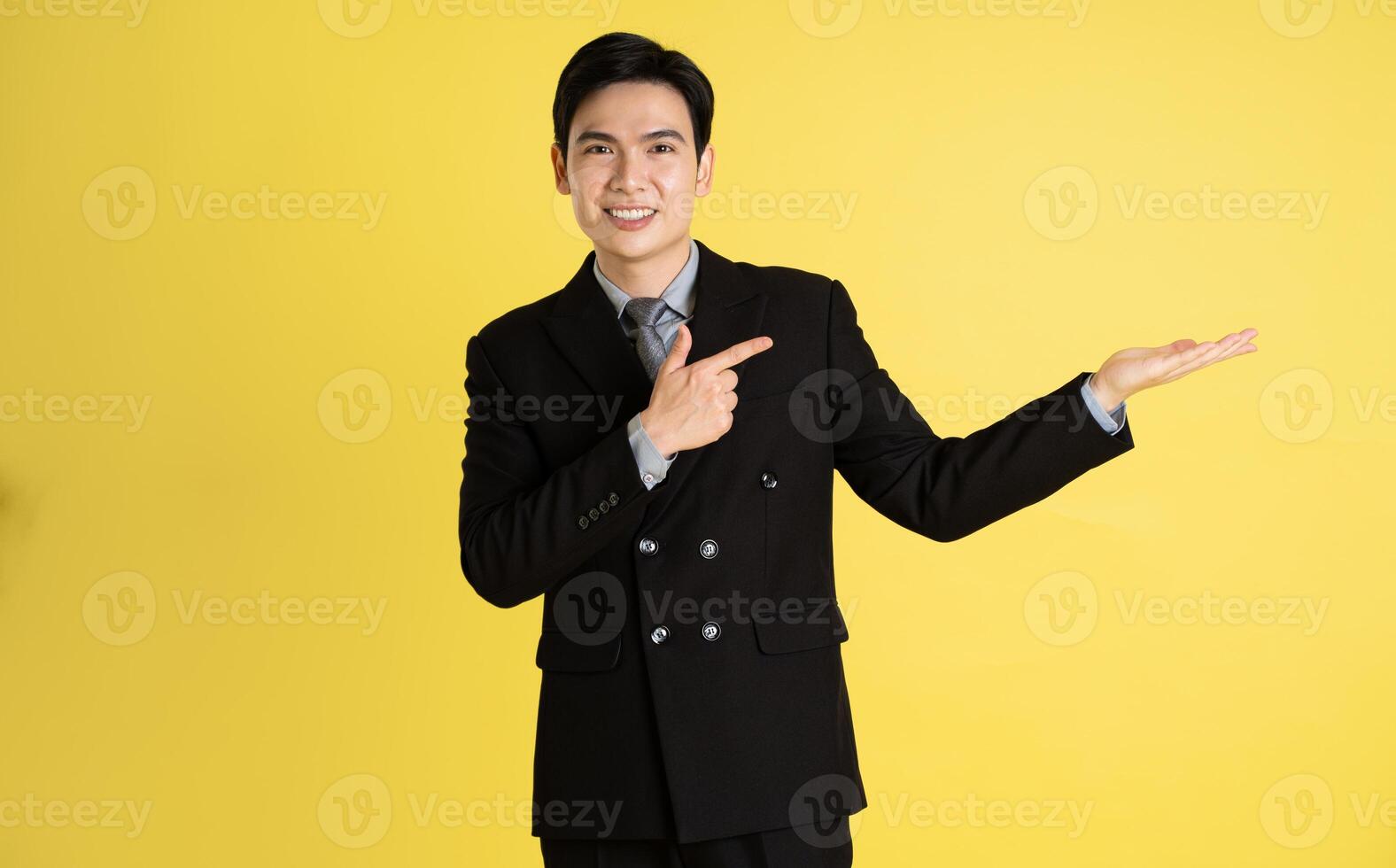 retrato de asiático masculino empresario. vistiendo un traje y posando en un amarillo antecedentes foto