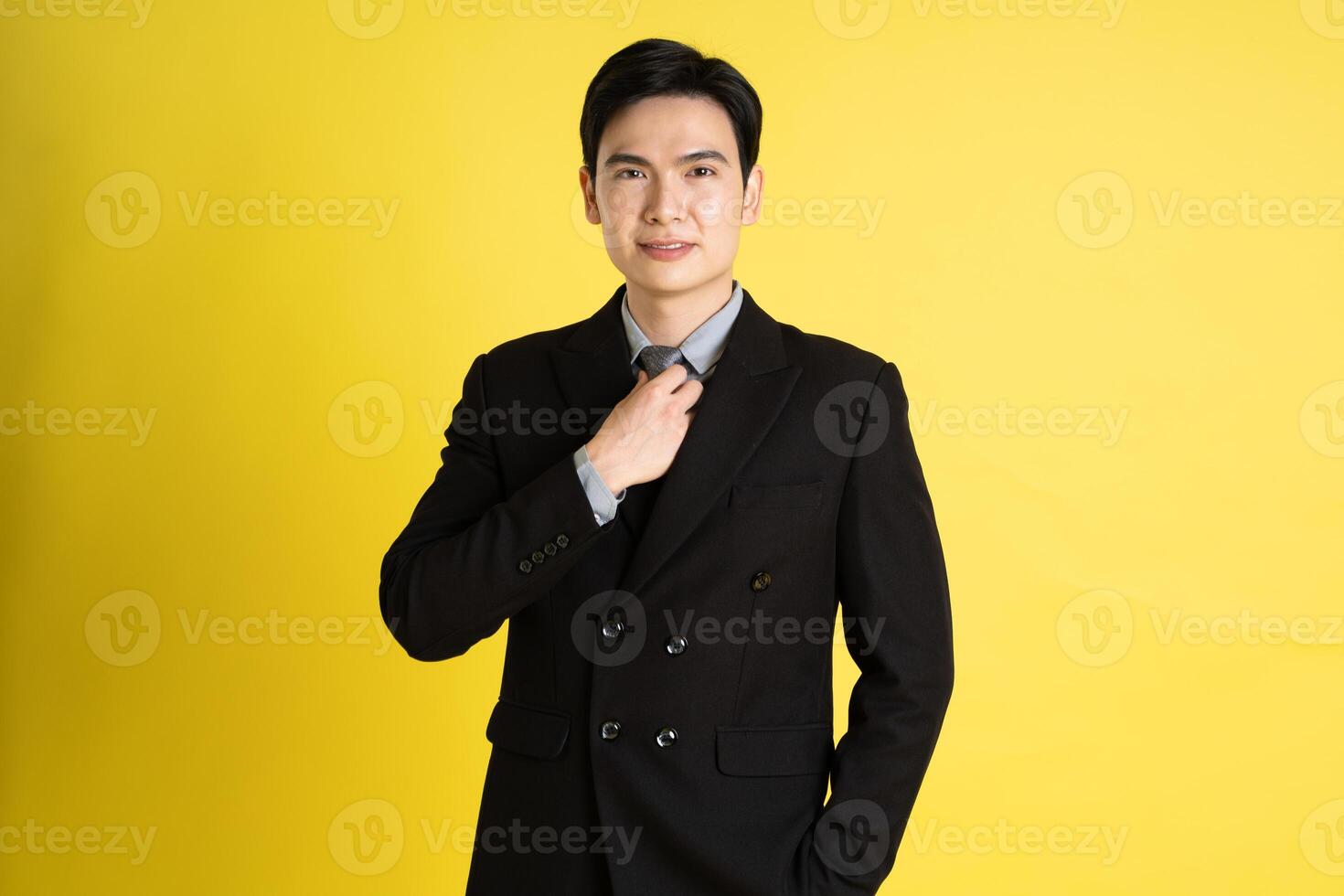 Portrait of Asian male businessman. wearing a suit and posing on a yellow background photo