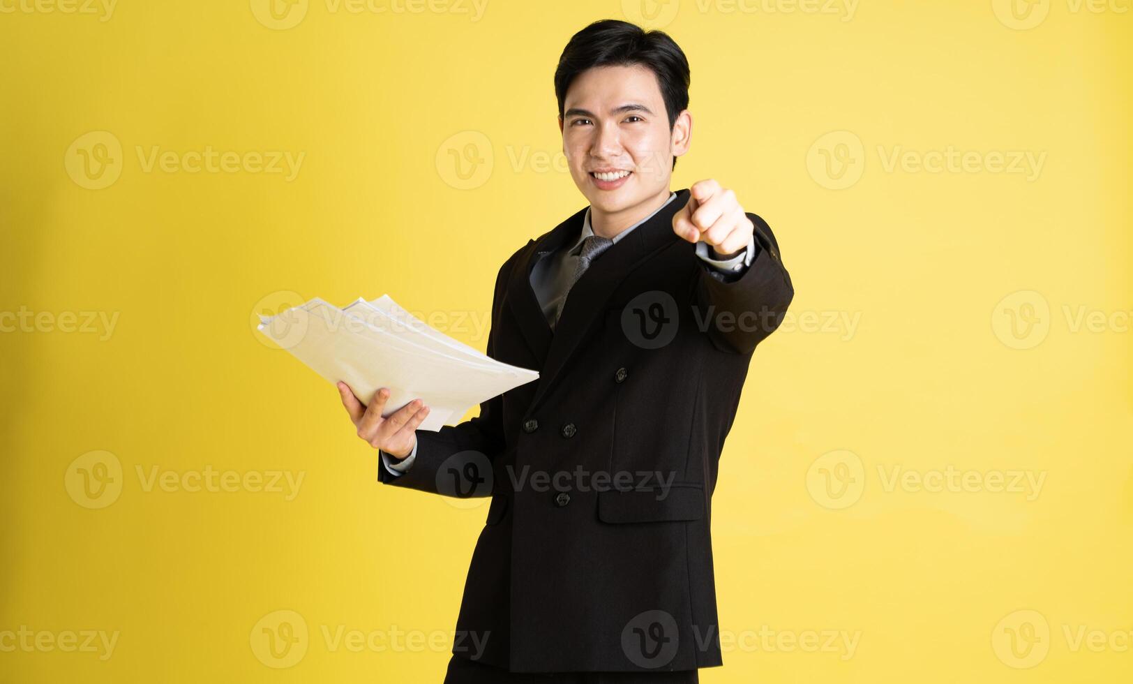 retrato de asiático masculino empresario. vistiendo un traje y posando en un amarillo antecedentes foto