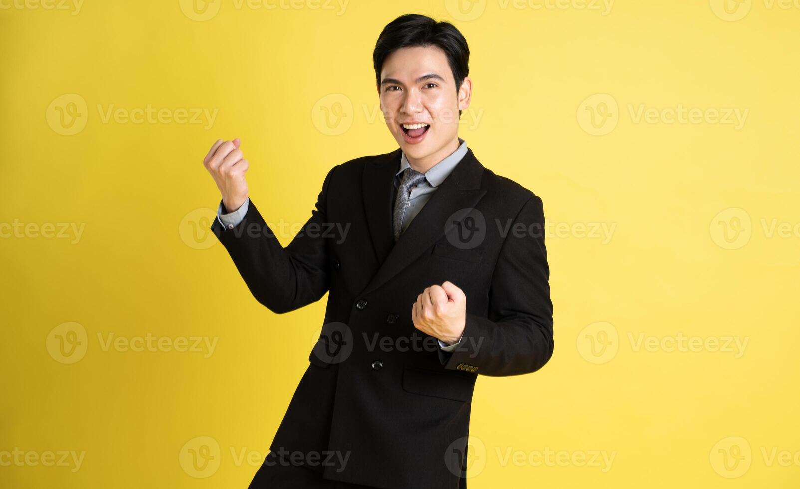 Portrait of Asian male businessman. wearing a suit and posing on a yellow background photo