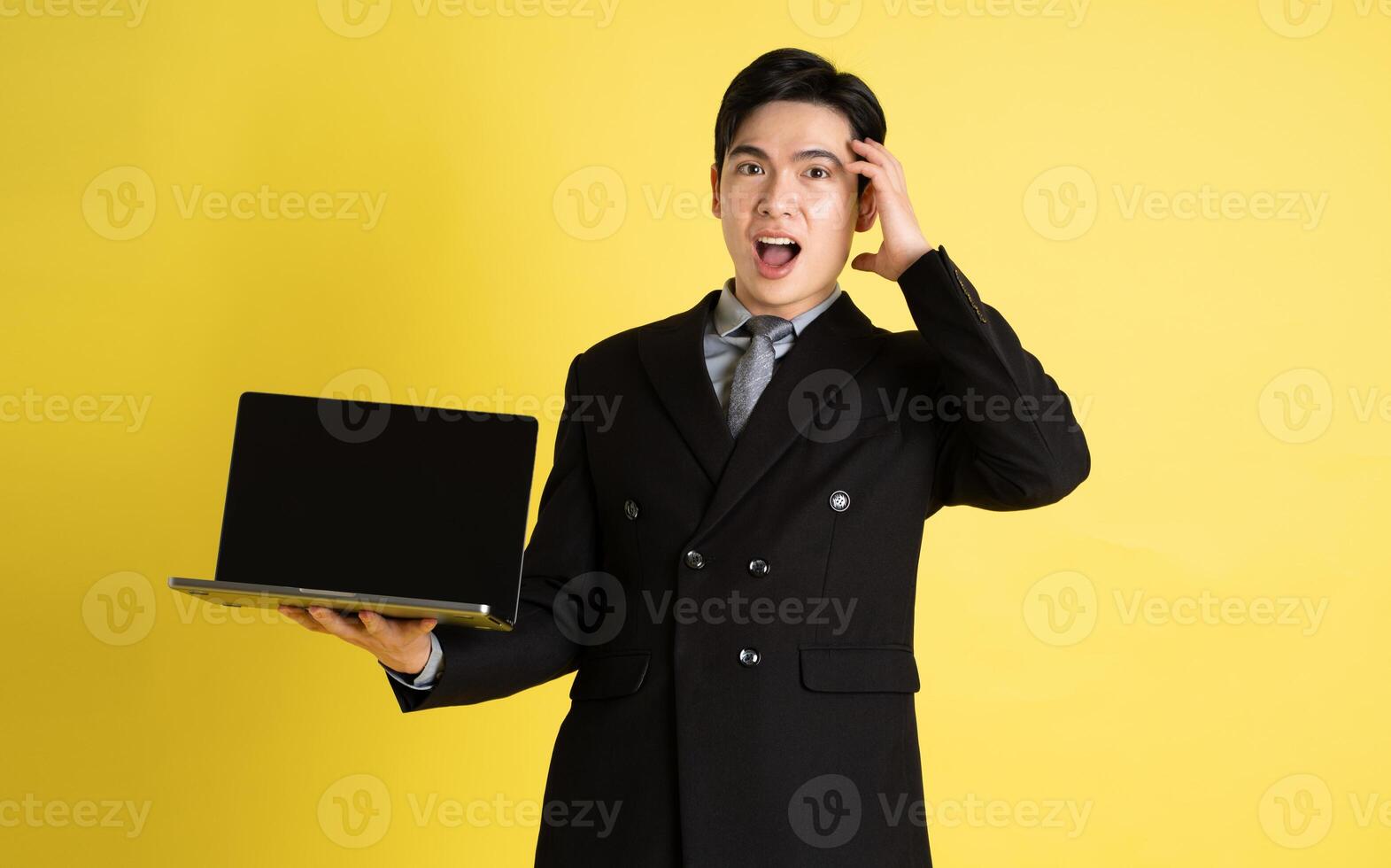 Portrait of Asian male businessman. wearing a suit and posing on a yellow background photo