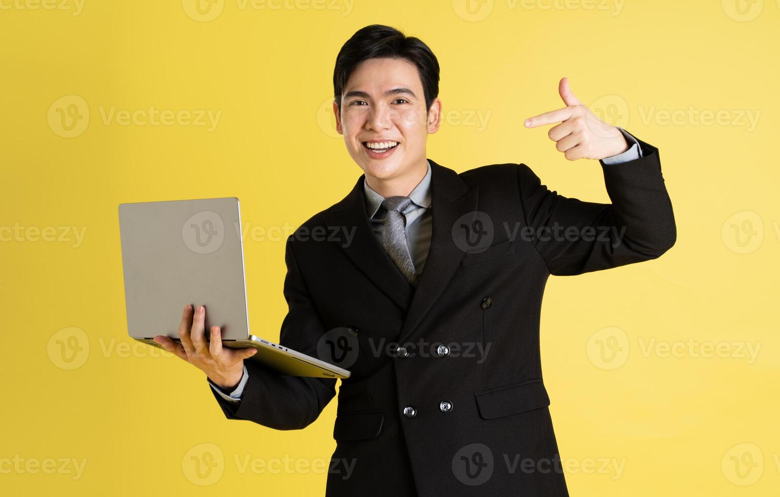 Portrait of Asian male businessman. wearing a suit and posing on a yellow background photo