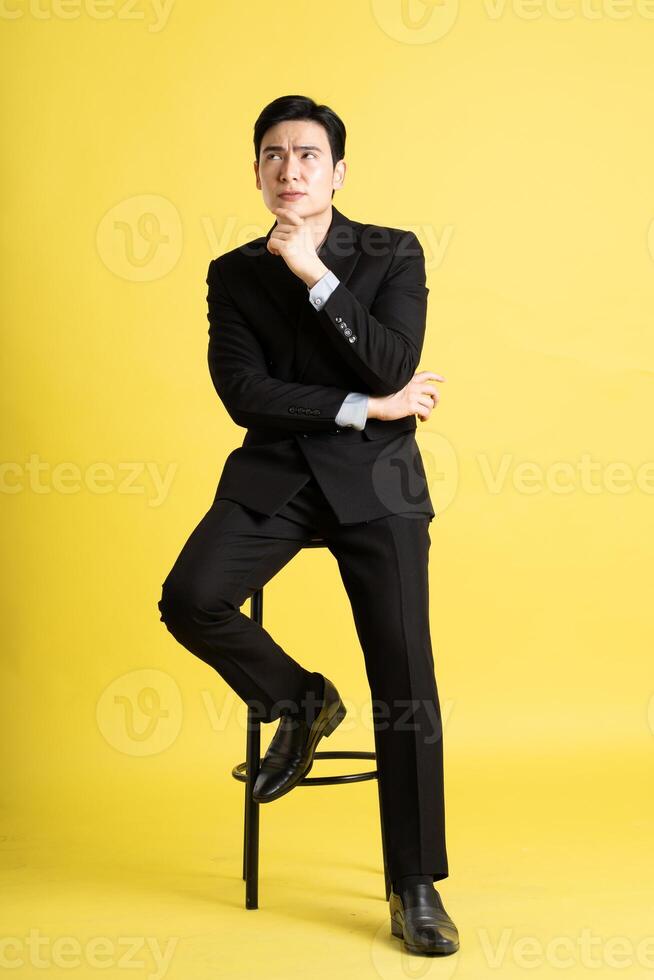 Portrait of Asian male businessman. wearing a suit and posing on a yellow background photo