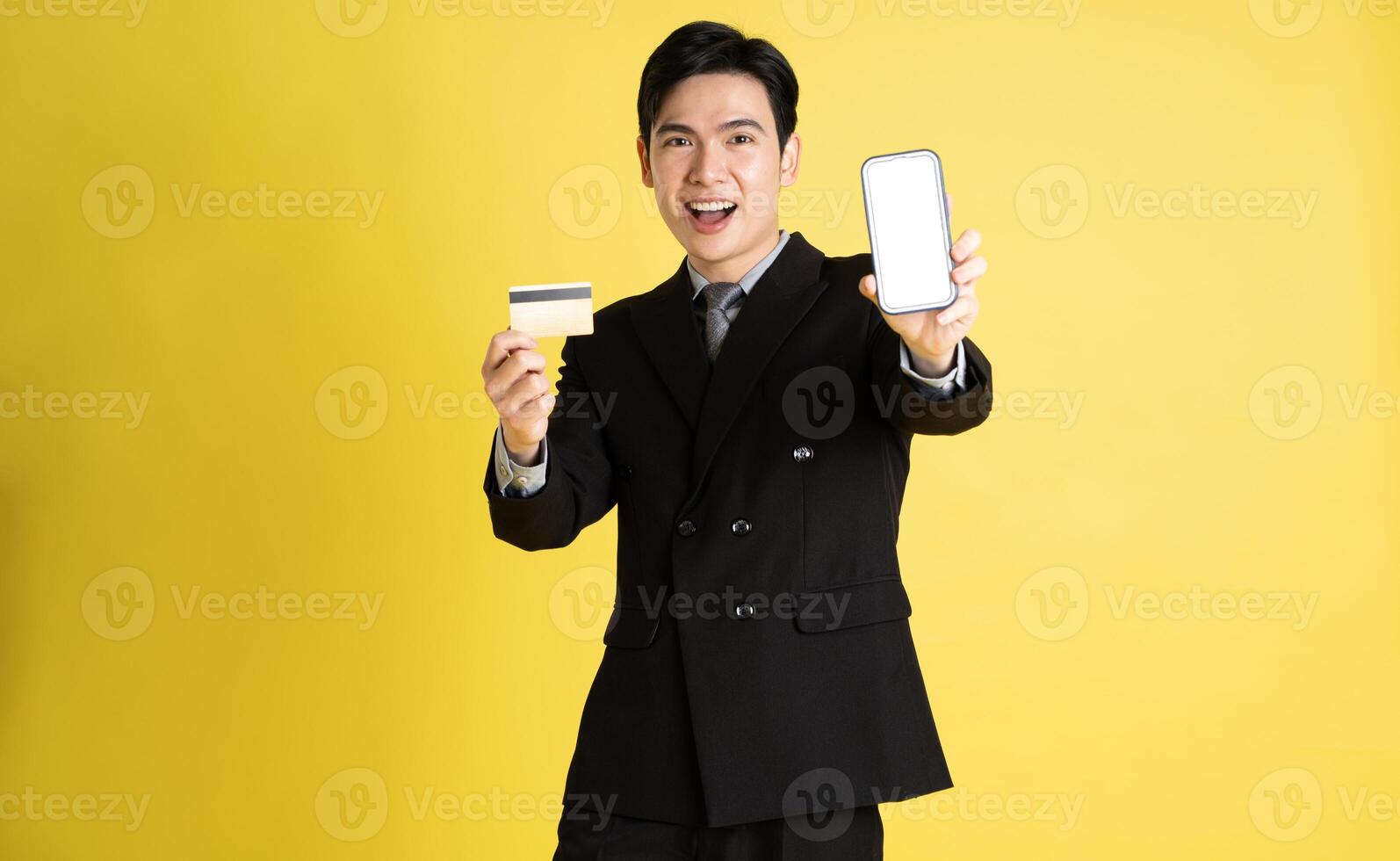Portrait of Asian male businessman. wearing a suit and posing on a yellow background photo