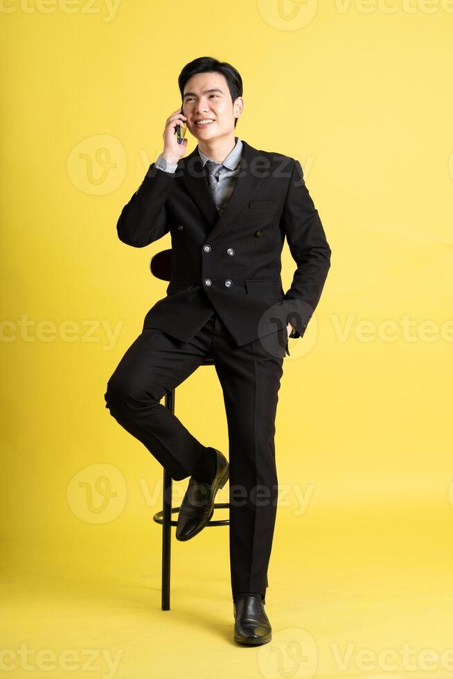 Portrait of Asian male businessman. wearing a suit and posing on a yellow background photo