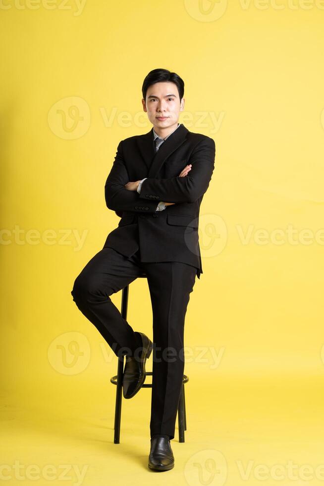 Portrait of Asian male businessman. wearing a suit and posing on a yellow background photo