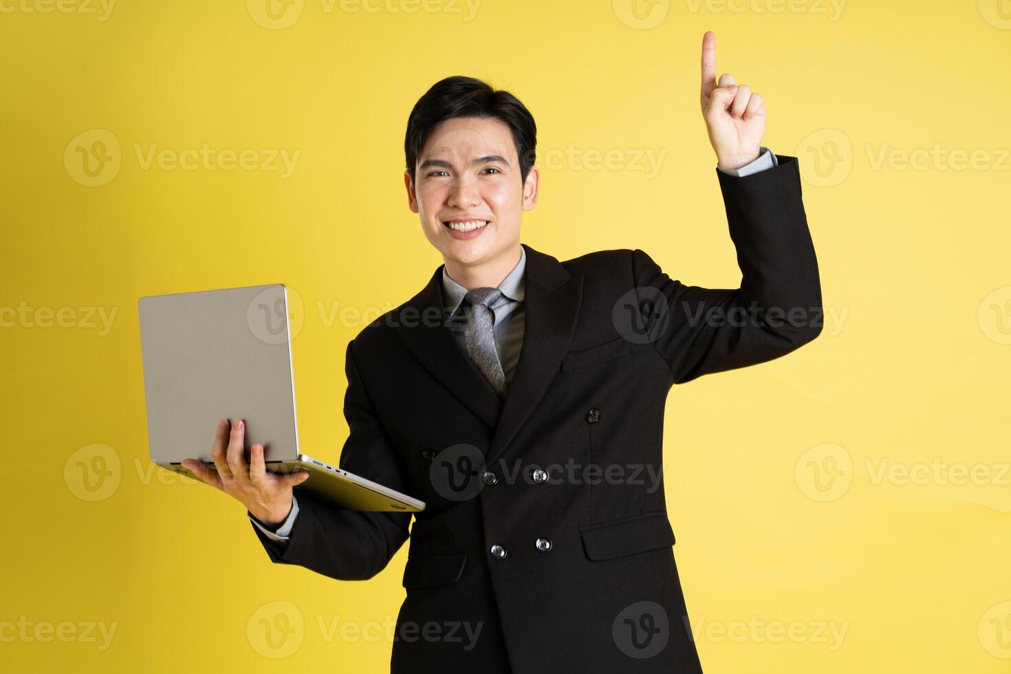 Portrait of Asian male businessman. wearing a suit and posing on a yellow background photo