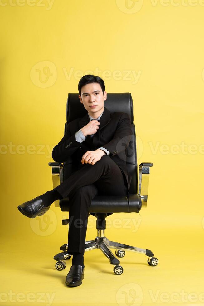 Portrait of Asian male businessman. wearing a suit and posing on a yellow background photo