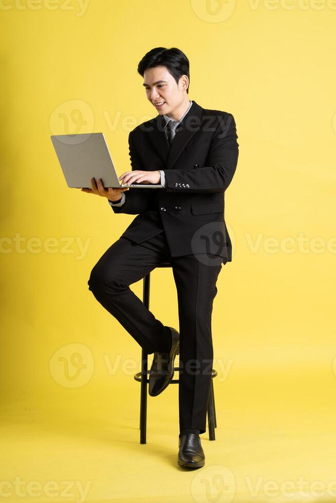 Portrait of Asian male businessman. wearing a suit and posing on a yellow background photo