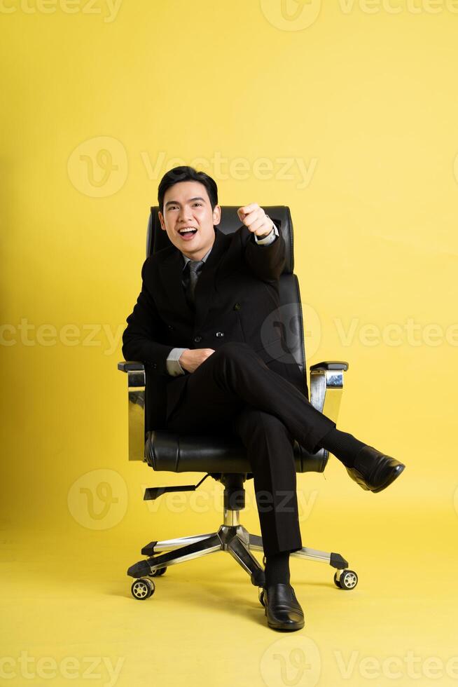 Portrait of Asian male businessman. wearing a suit and posing on a yellow background photo