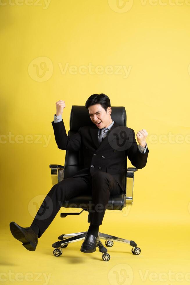Portrait of Asian male businessman. wearing a suit and posing on a yellow background photo