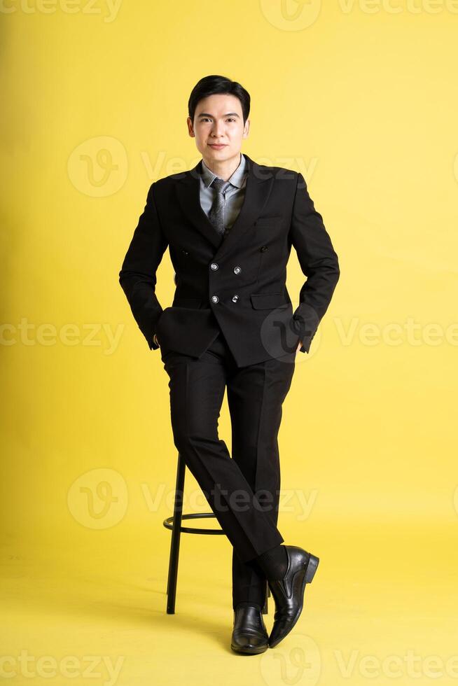 retrato de asiático masculino empresario. vistiendo un traje y posando en un amarillo antecedentes foto