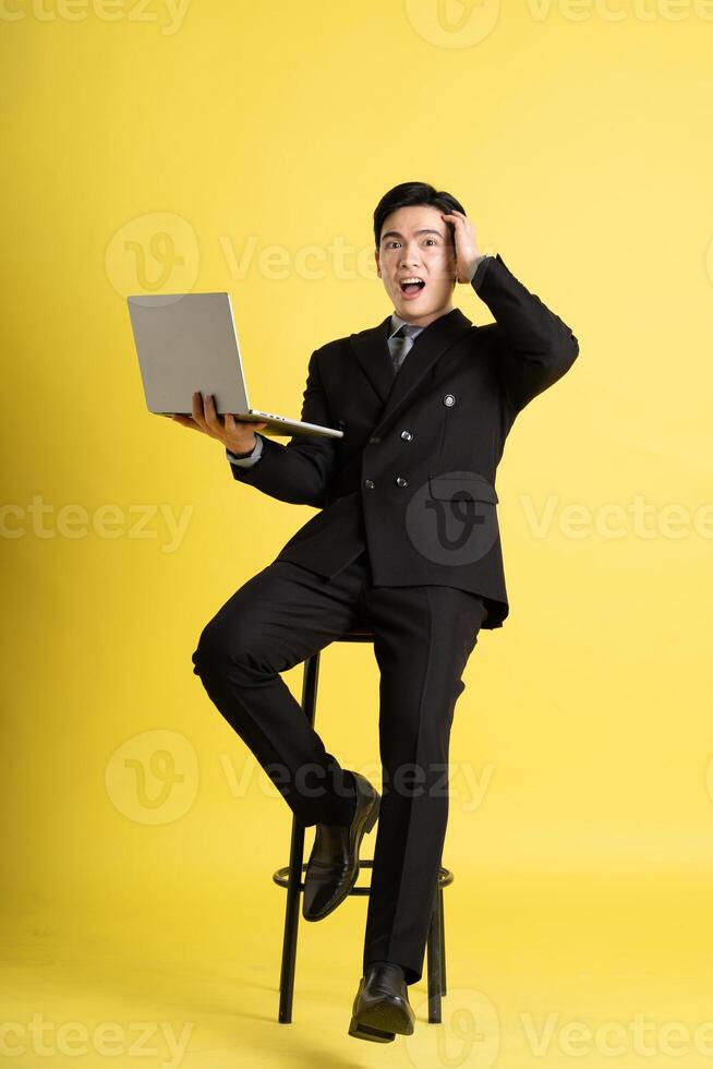 Portrait of Asian male businessman. wearing a suit and posing on a yellow background photo