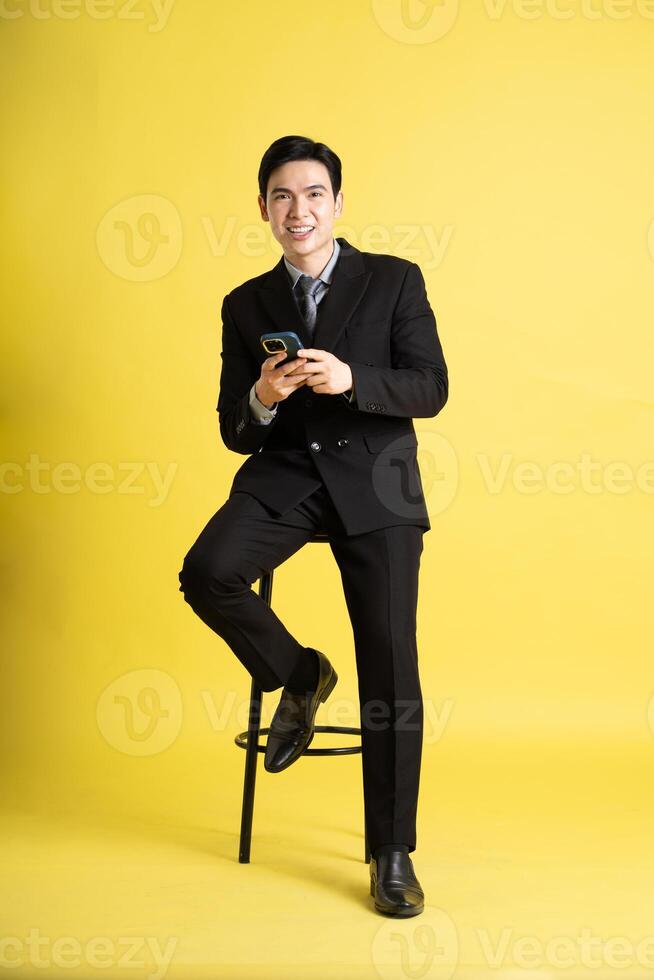 Portrait of Asian male businessman. wearing a suit and posing on a yellow background photo