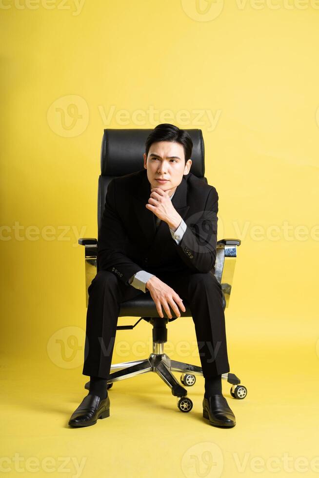 Portrait of Asian male businessman. wearing a suit and posing on a yellow background photo