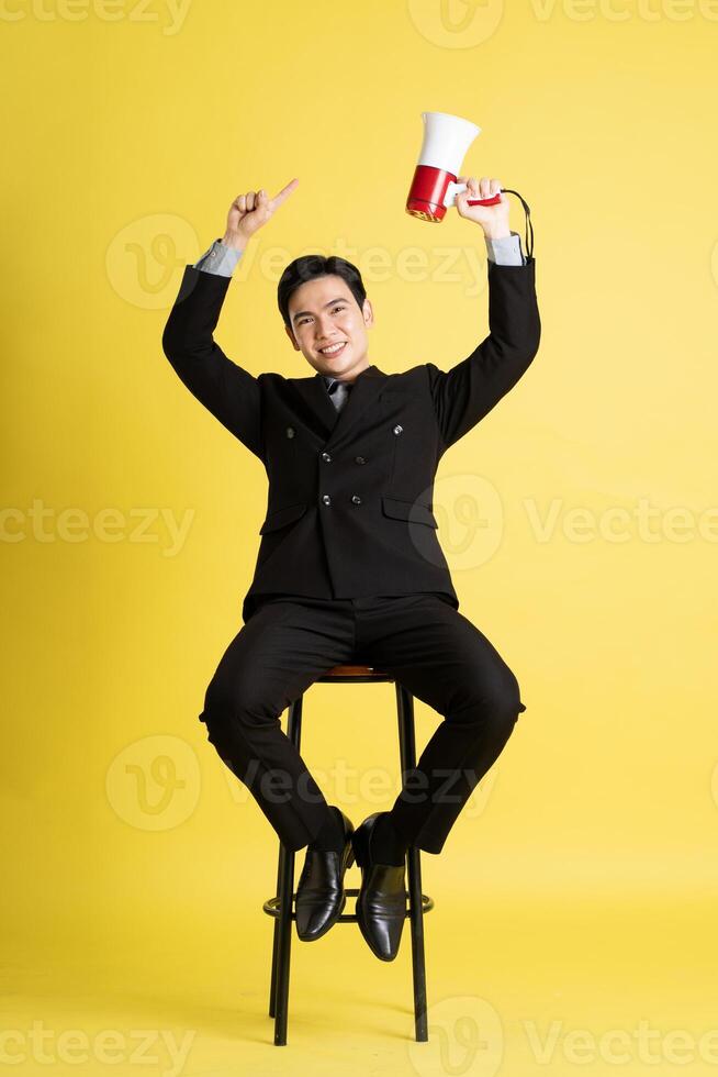 Portrait of Asian male businessman. wearing a suit and posing on a yellow background photo