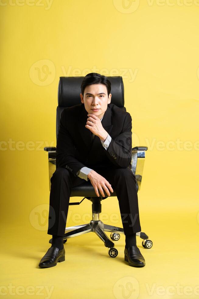 retrato de asiático masculino empresario. vistiendo un traje y posando en un amarillo antecedentes foto