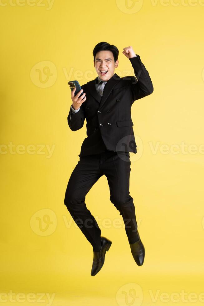 Portrait of Asian male businessman. wearing a suit and posing on a yellow background photo