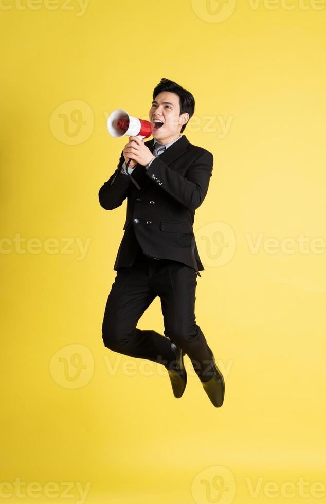 Portrait of Asian male businessman. wearing a suit and posing on a yellow background photo