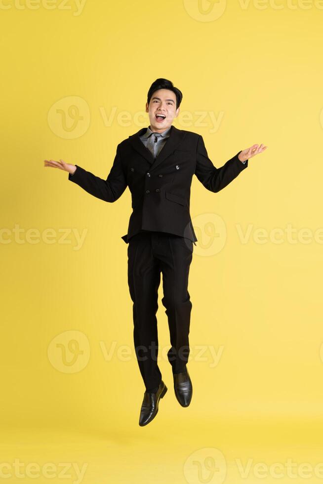 Portrait of Asian male businessman. wearing a suit and posing on a yellow background photo