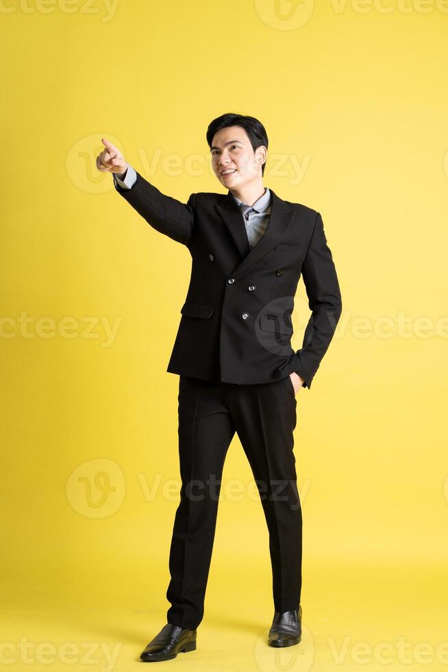 Portrait of Asian male businessman. wearing a suit and posing on a yellow background photo