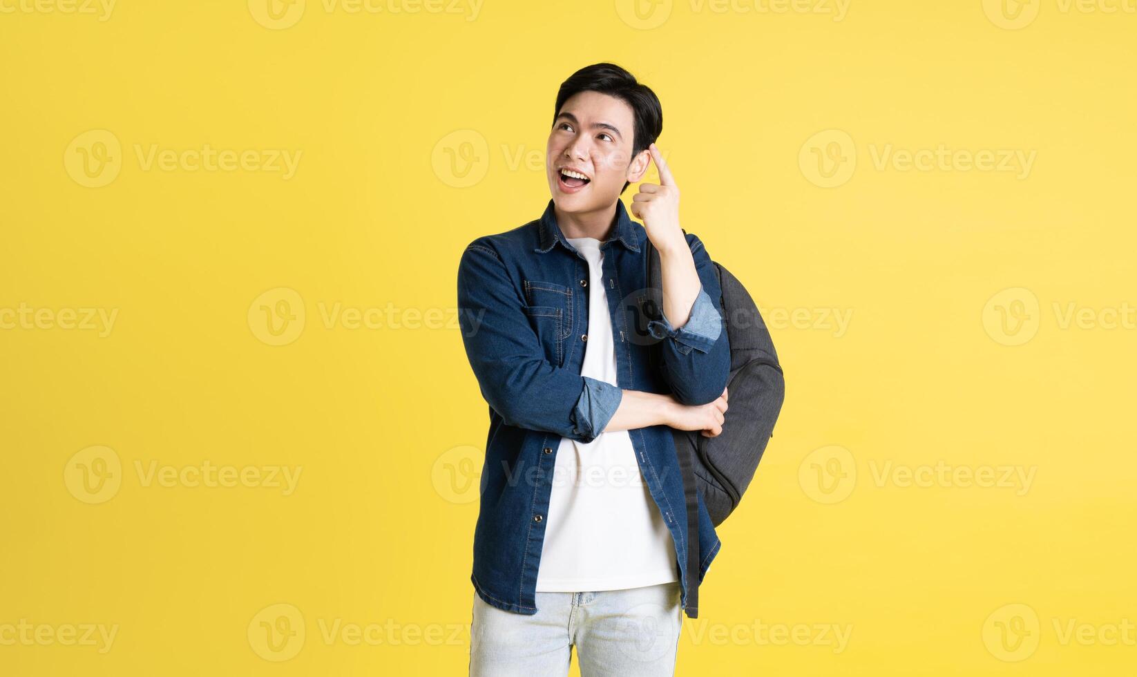 Portrait of Asian male student posing on yellow background photo