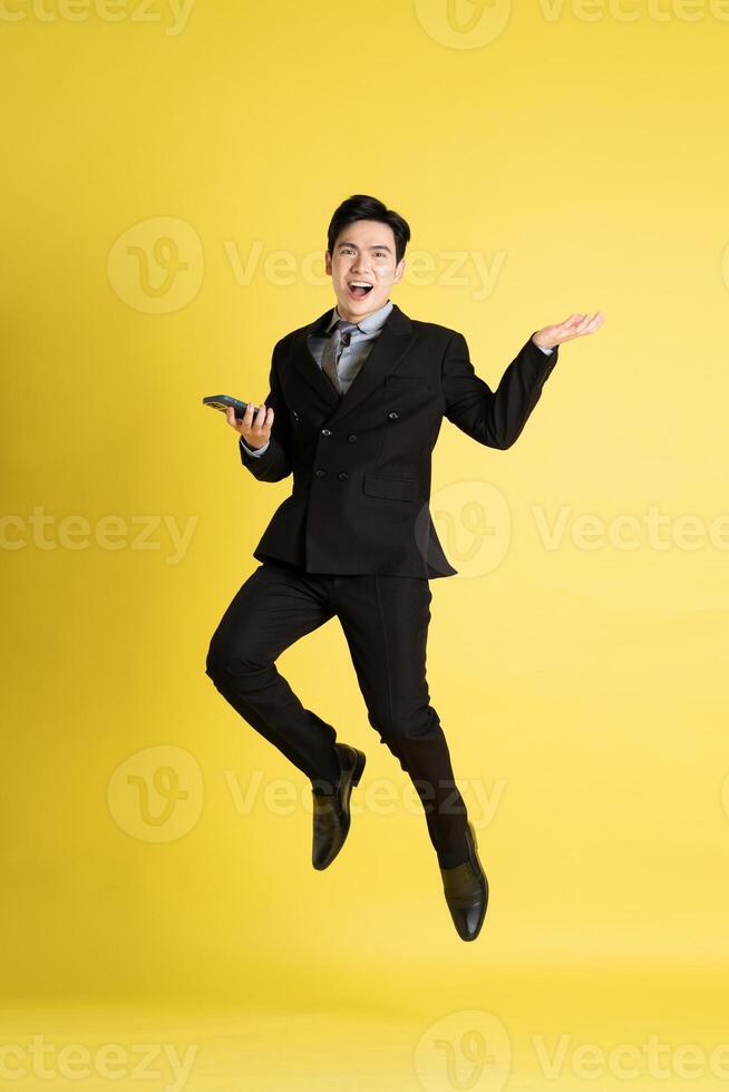 Portrait of Asian male businessman. wearing a suit and posing on a yellow background photo