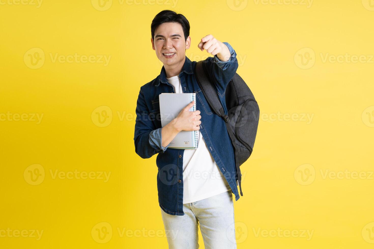 Portrait of Asian male student posing on yellow background photo