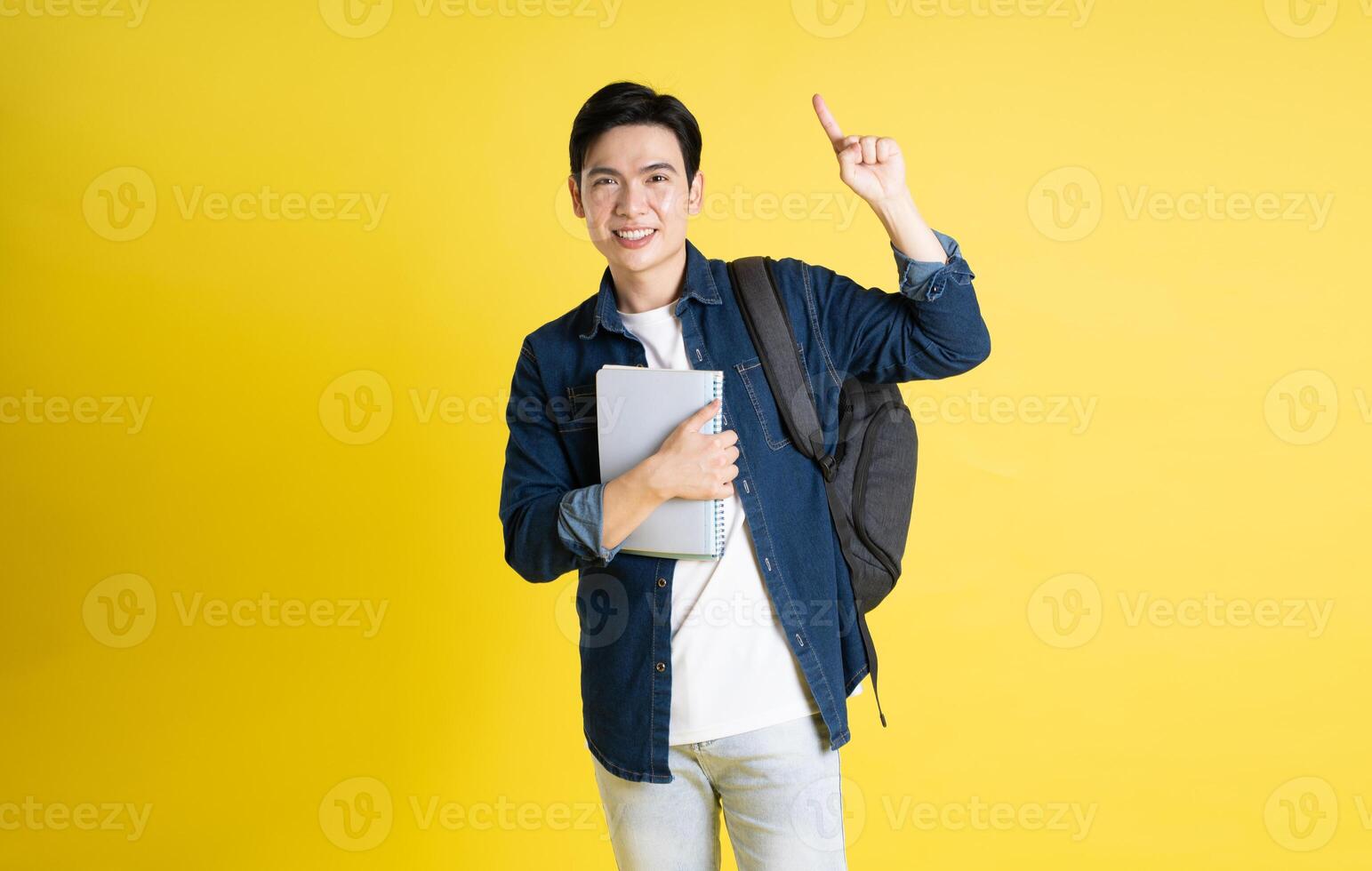 retrato de asiático masculino estudiante posando en amarillo antecedentes foto