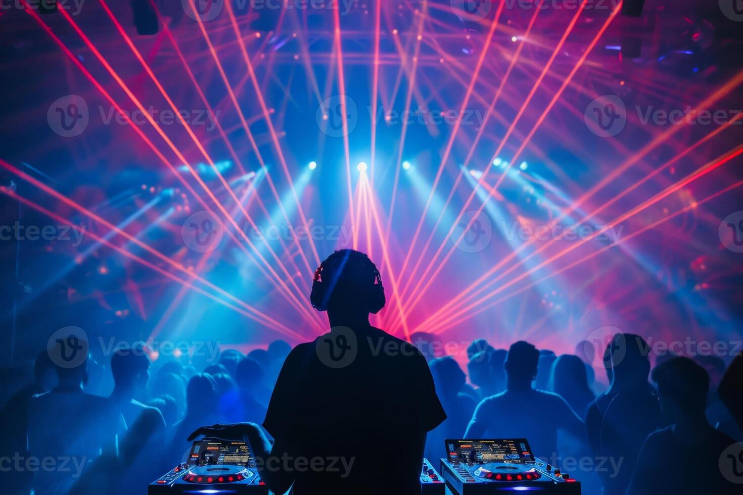 Male DJ on a big rave playing for a big crowd of party people, ravers dancing, big laser show photo
