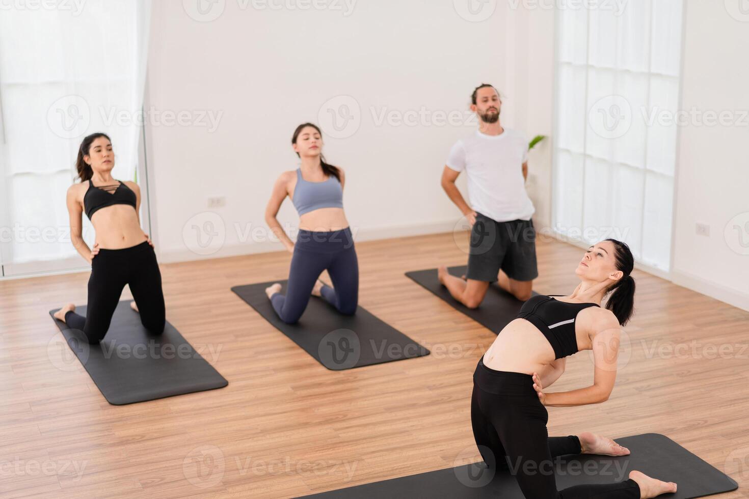 un yoga profesor y su grupo de estudiantes hacer básico yoga poses en un salón de clases en un aptitud centrar en el estudio. foto