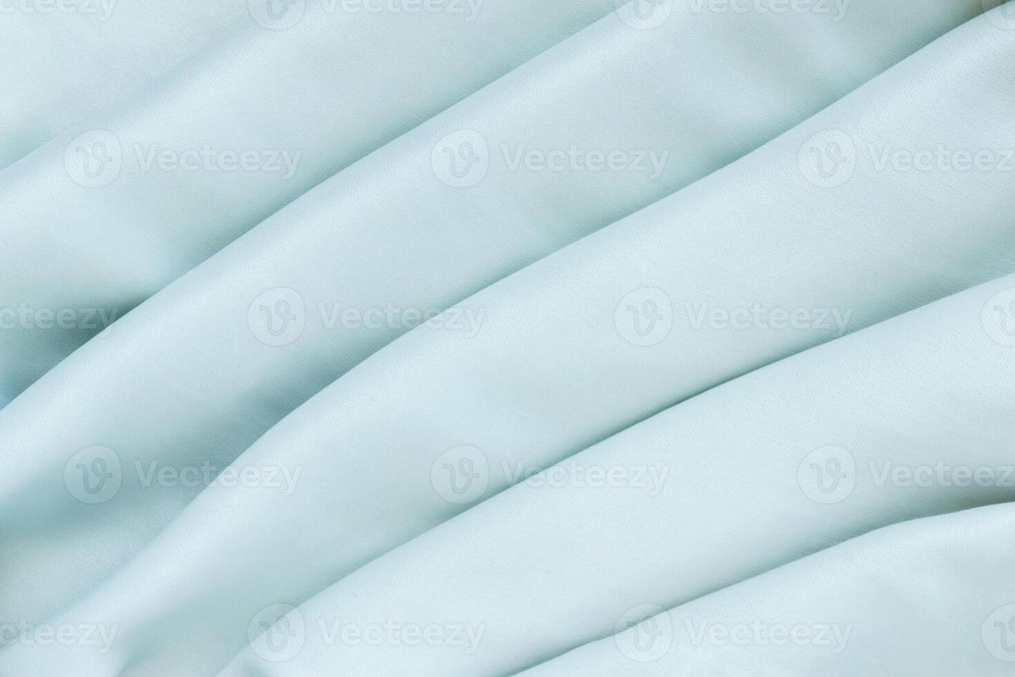 Silk draped mint fabric with pleats. Textured background of delicate green color. photo
