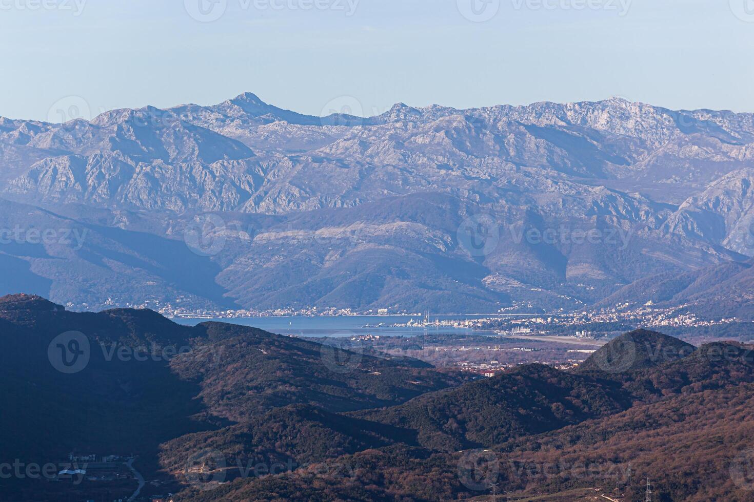 Picturesque panoramic view of the city, sea and mountain range under blue skies across green hills in summer. Background. For text. Banner. Postcard. Horizontal photo
