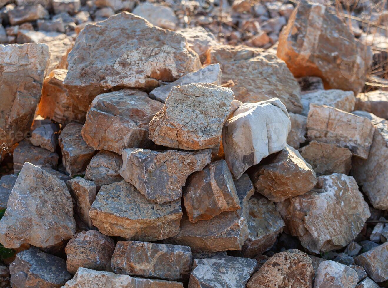 Stone wall of large mountain stones with burrs. A mountain of grey cobbles. Texture. Background. Horizontal photo