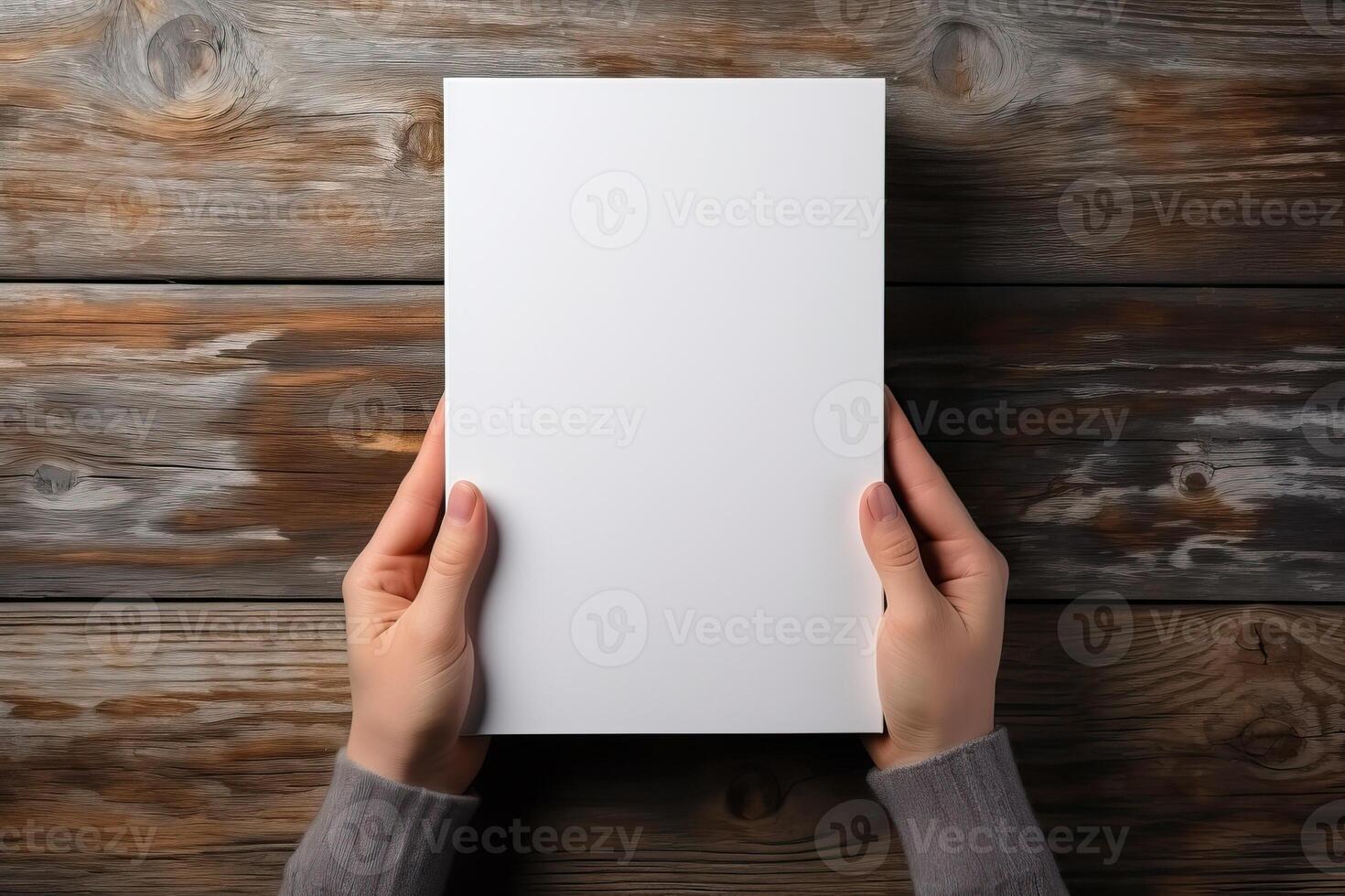 A man holds a sheet of A4 format in his hands on a wooden background. photo