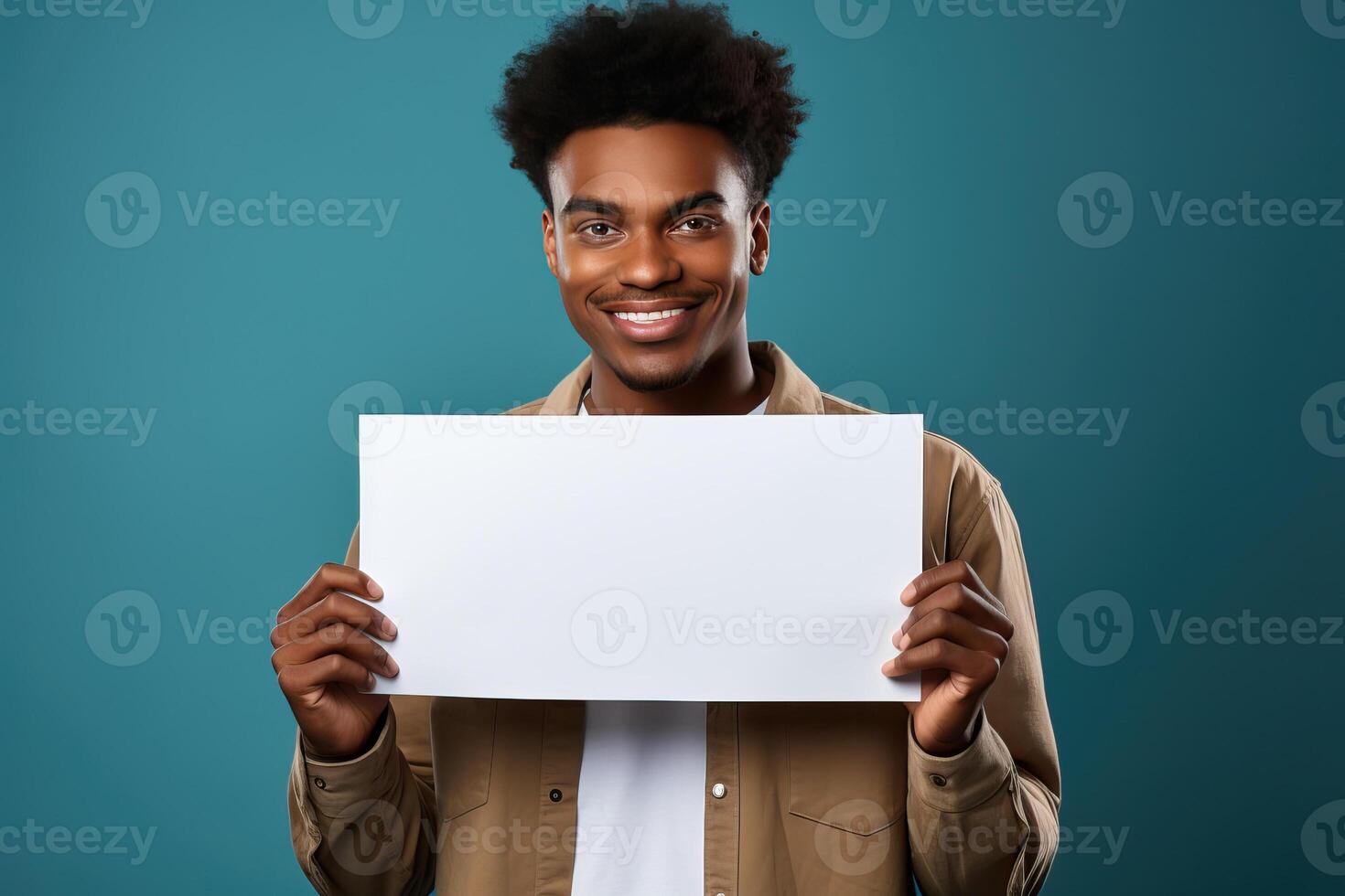 A guy of African appearance holds in his hands a white blank sheet of paper with a place for writing or mockup. photo