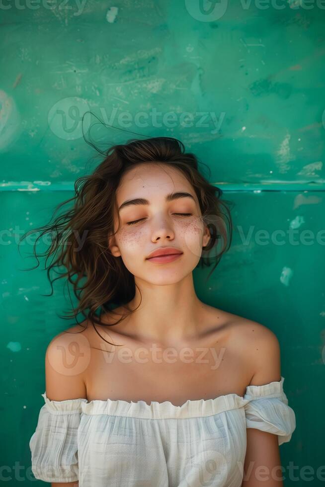 Portrait of young beautiful woman standing in front of the green wall photo