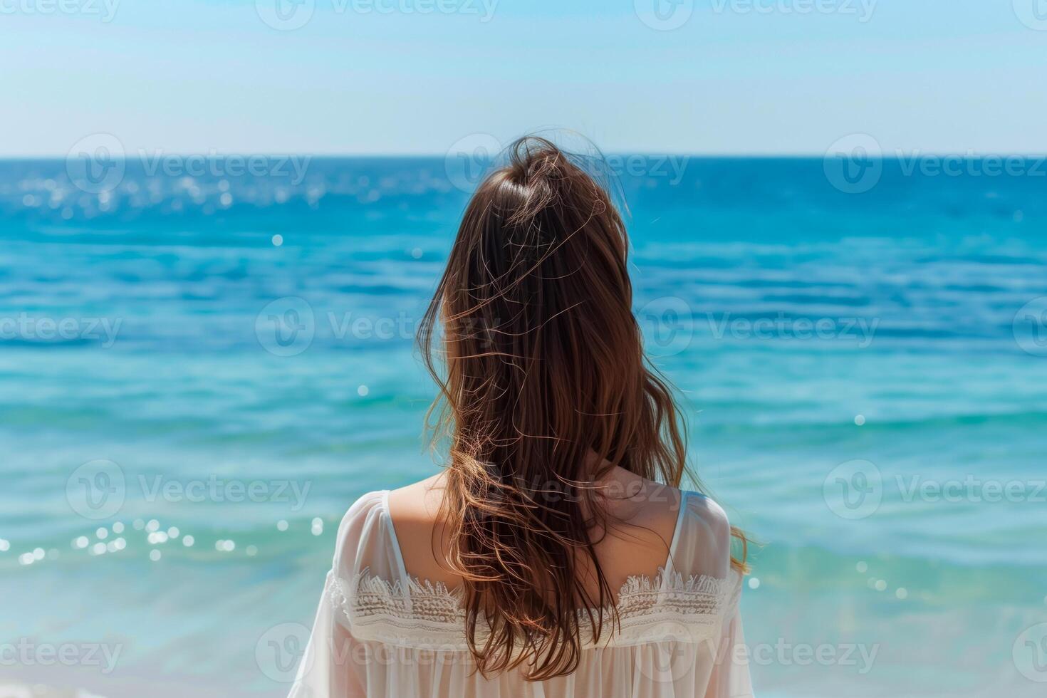 A woman looks towards the sea, rear view. Minimal pastel colors. photo