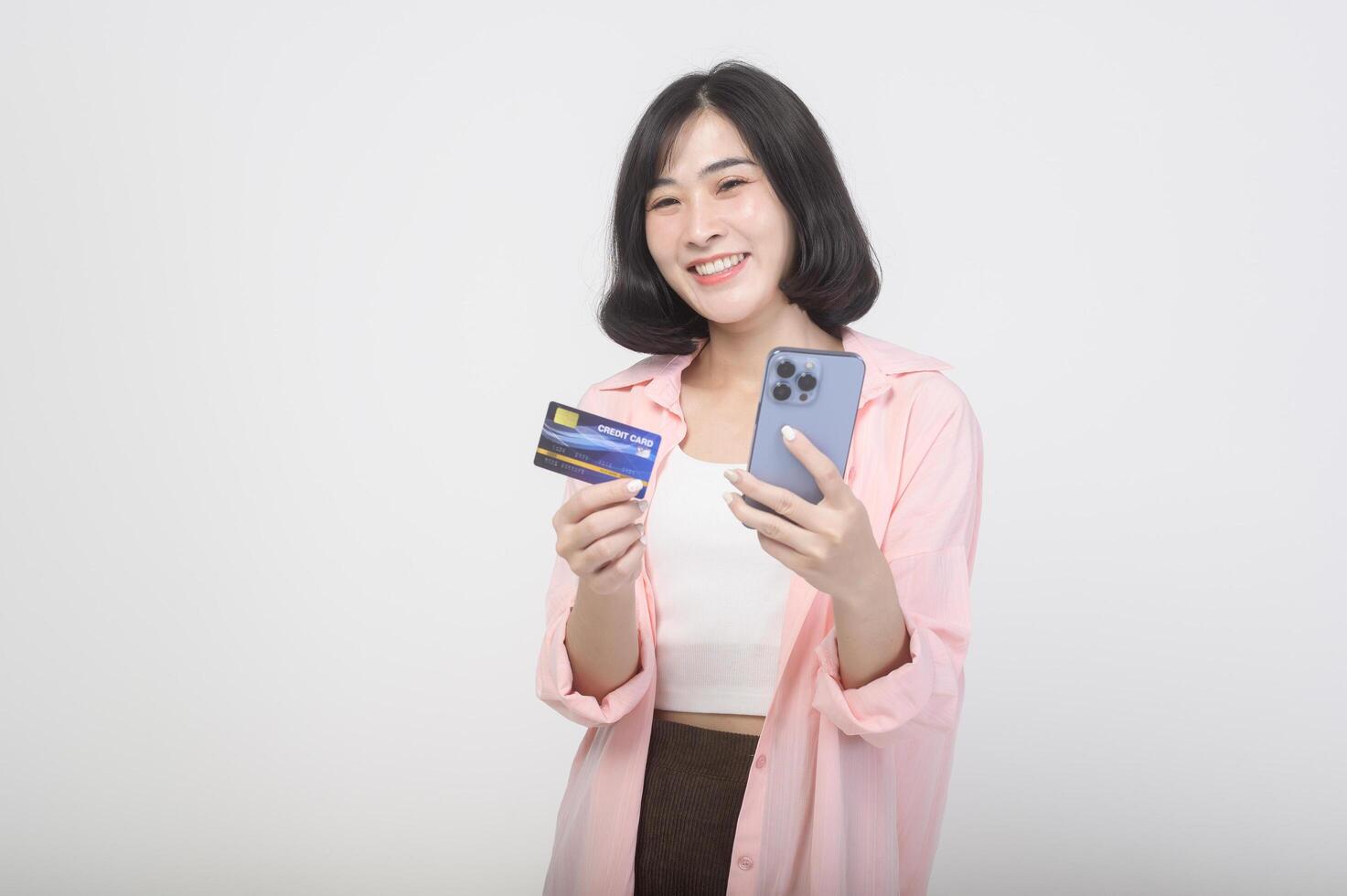 Asian smiling woman holding credit card over white background studio, shopping and finance concept. photo