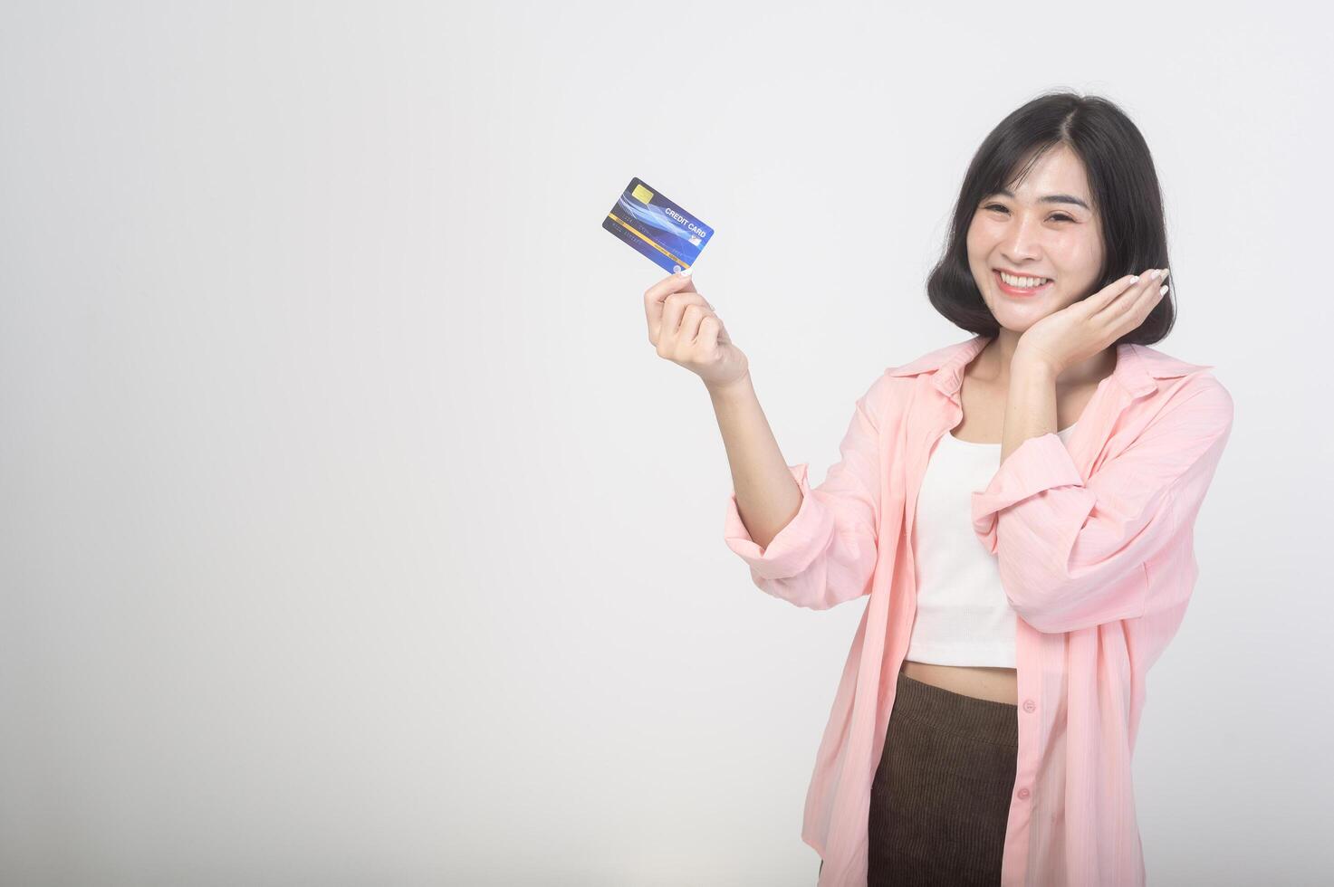 Asian smiling woman holding credit card over white background studio, shopping and finance concept. photo