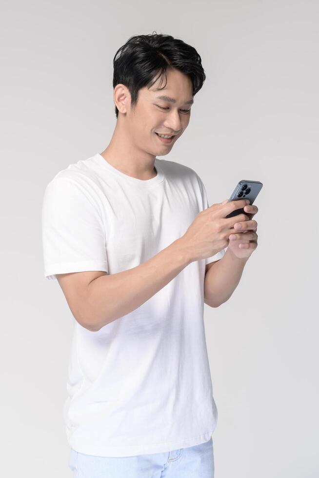 Portrait of young smiling asian man using smartphone over white background photo