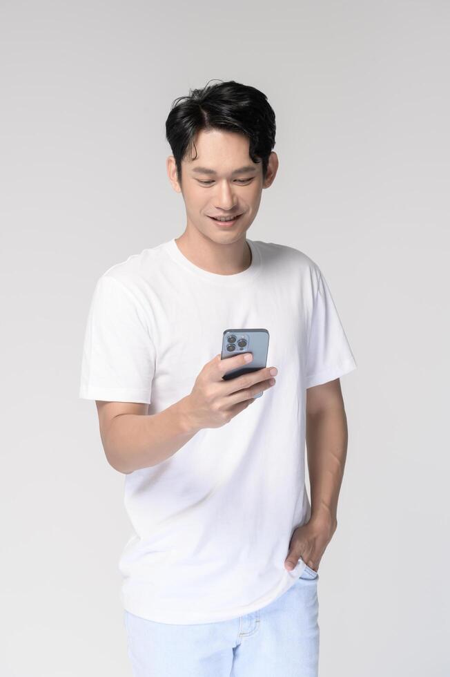 Portrait of young smiling asian man using smartphone over white background photo