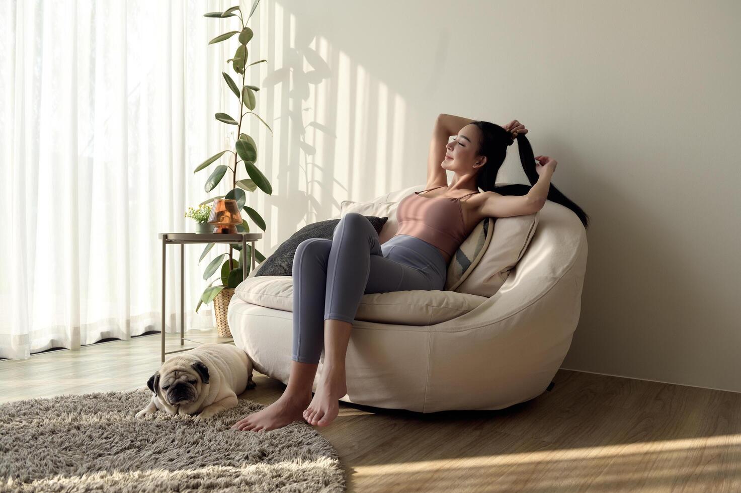 Happy young asian woman cuddling and spending time with cute dog in living room. photo