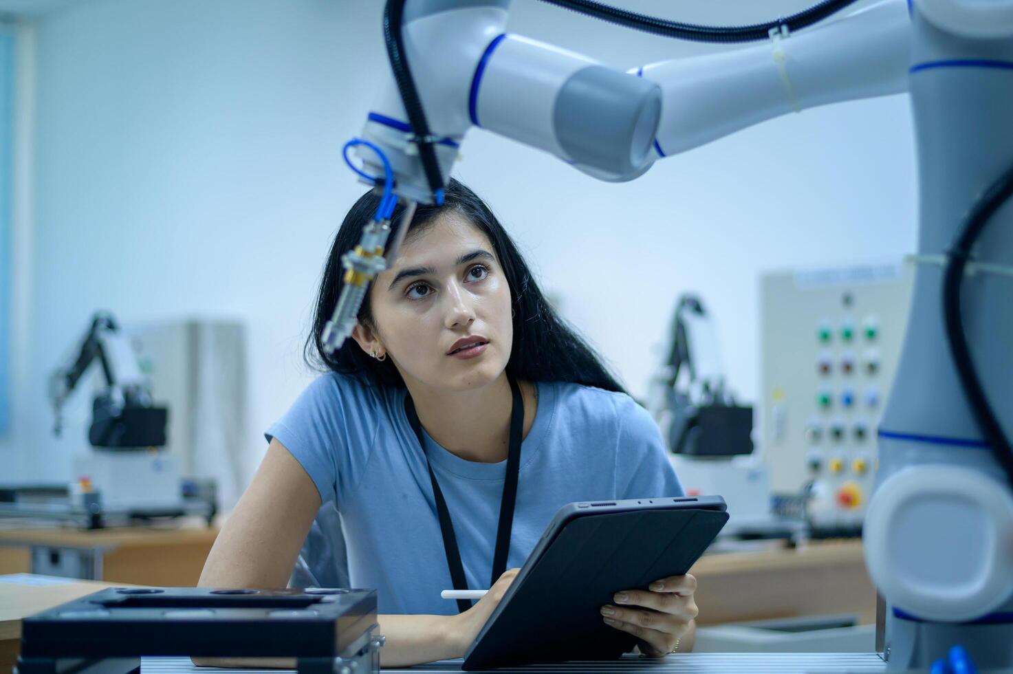 Female Robotics engineer working with Programming and Manipulating Robot Hand, Industrial Robotics Design, High Tech Facility, Modern Machine Learning. Mass Production Automatics. photo