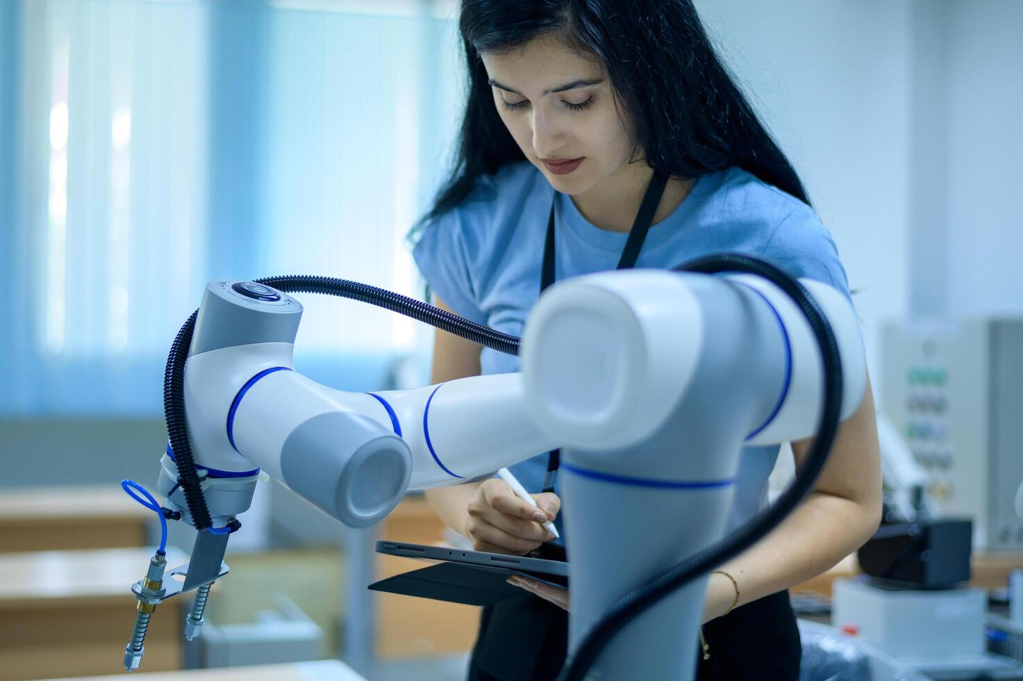 Female Robotics engineer working with Programming and Manipulating Robot Hand, Industrial Robotics Design, High Tech Facility, Modern Machine Learning. Mass Production Automatics. photo