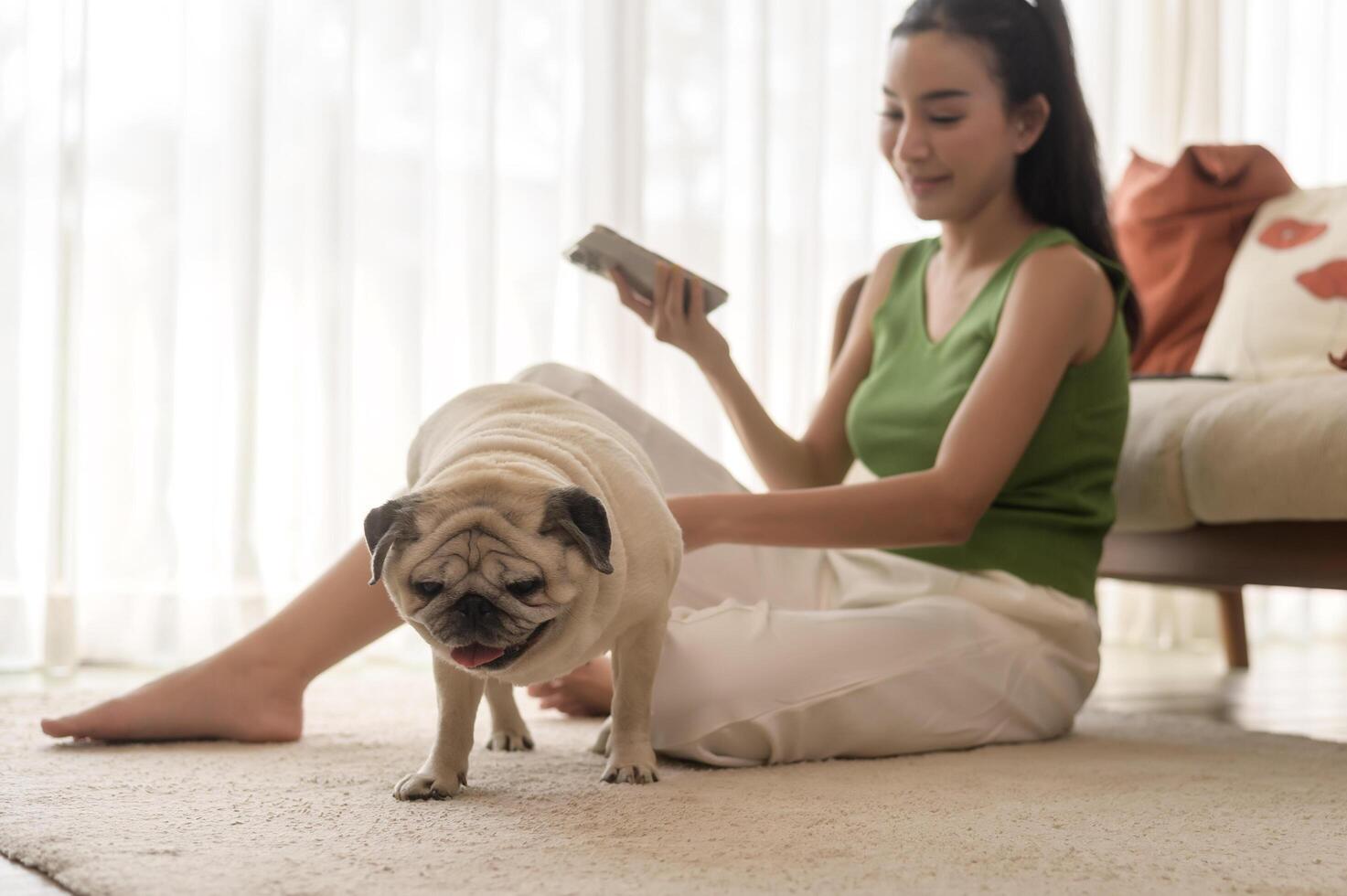 Happy young asian woman cuddling and spending time with cute dog in living room. photo