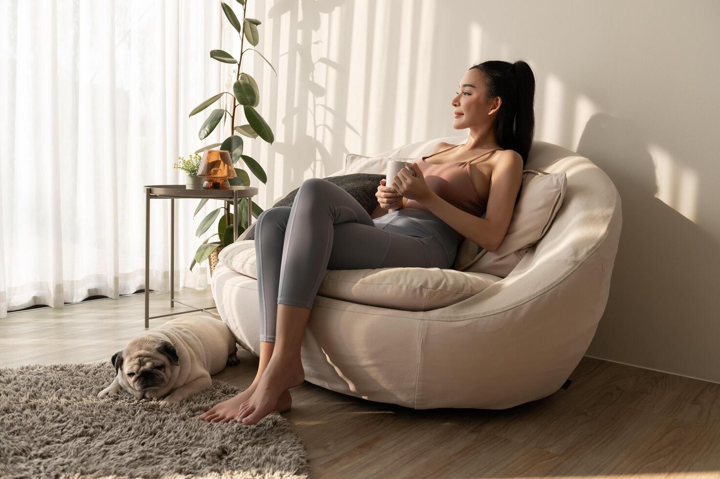 Young asian woman enjoying having coffee in living room at home photo