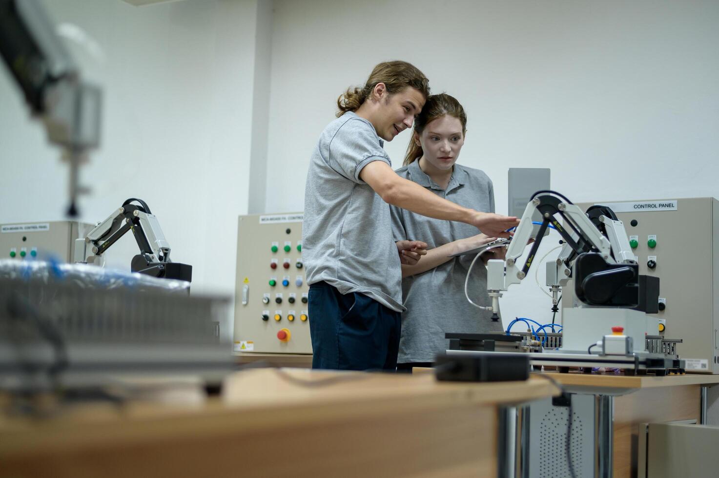 Trainee Robotics engineer learning with Programming and Manipulating Robot Hand, Industrial Robotics Design, High Tech Facility, Modern Machine Learning. Mass Production Automatics. photo