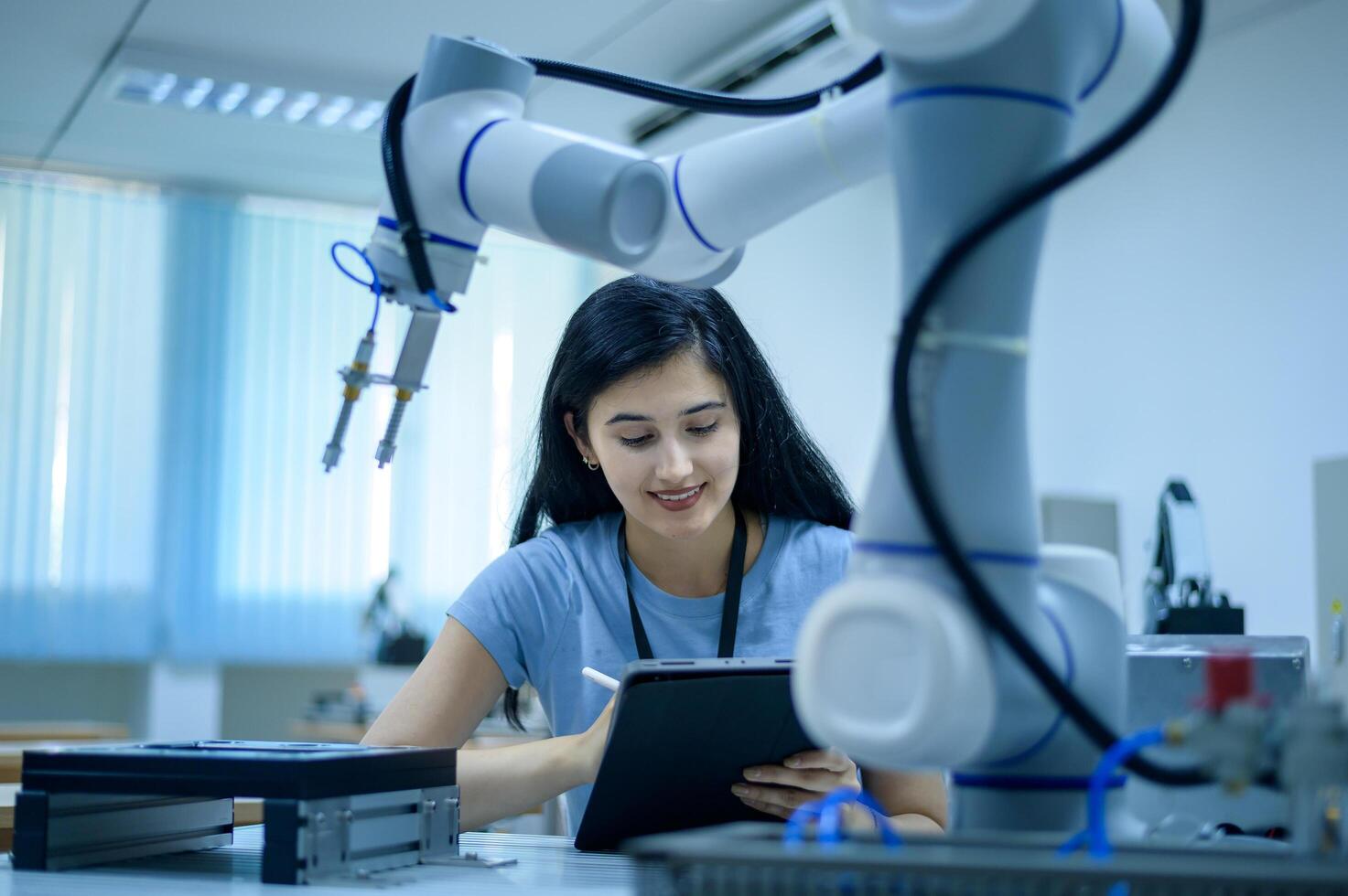 Female Robotics engineer working with Programming and Manipulating Robot Hand, Industrial Robotics Design, High Tech Facility, Modern Machine Learning. Mass Production Automatics. photo