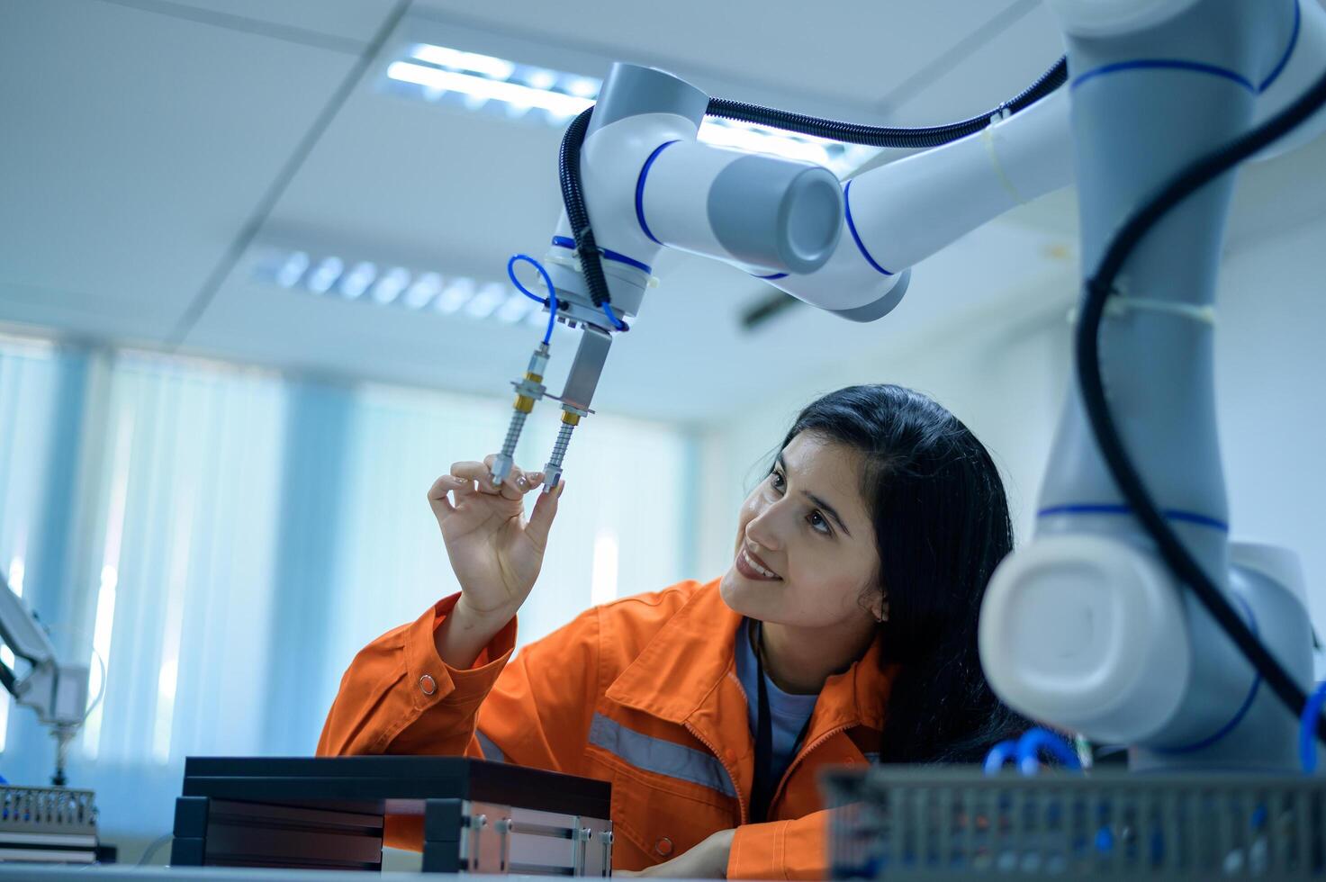 Female Robotics engineer working with Programming and Manipulating Robot Hand, Industrial Robotics Design, High Tech Facility, Modern Machine Learning. Mass Production Automatics. photo